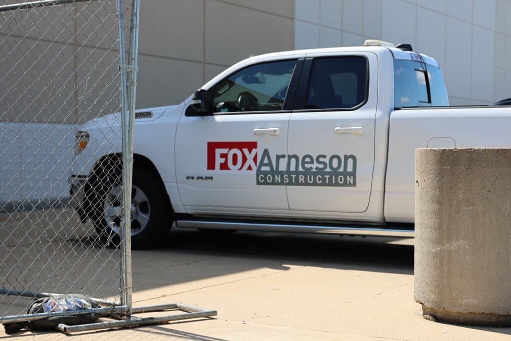 White Fox Arneson Construction pickup truck parked outside, partial view of front-side with company logo on door.