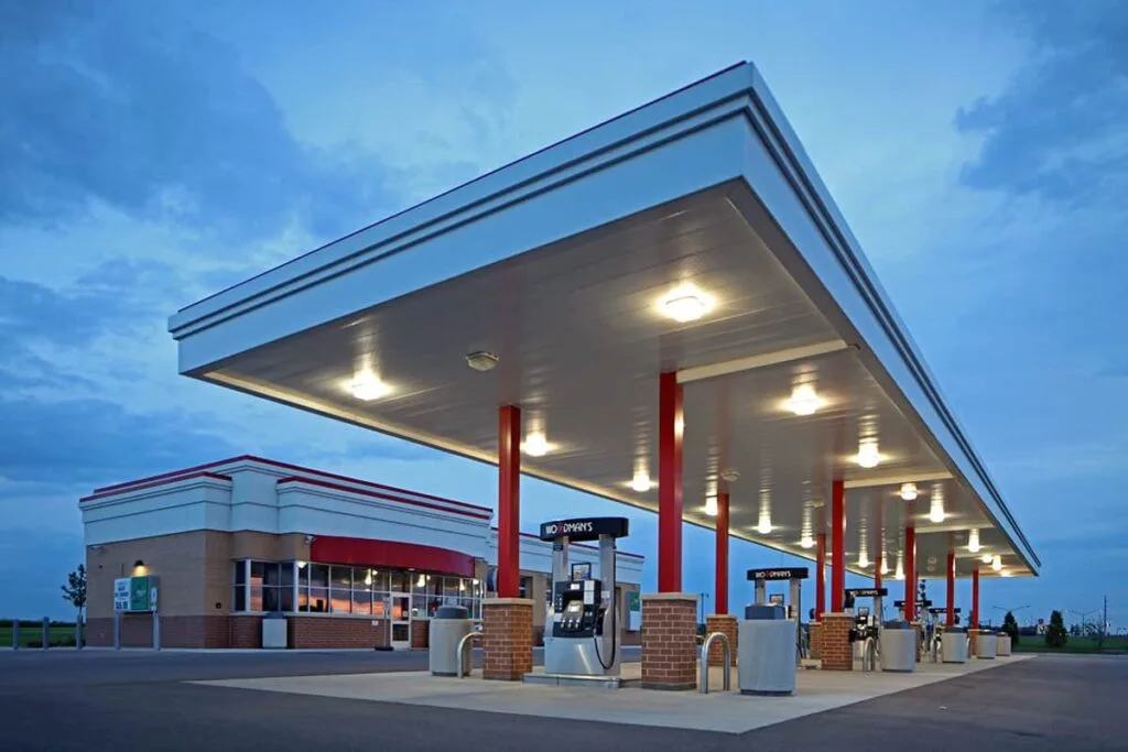 Exterior view of Woodman's Gas & Lube Center in Altoona, Wisconsin, featuring a gas station with multiple fuel pumps and a car wash bay, set against a clear blue sky.